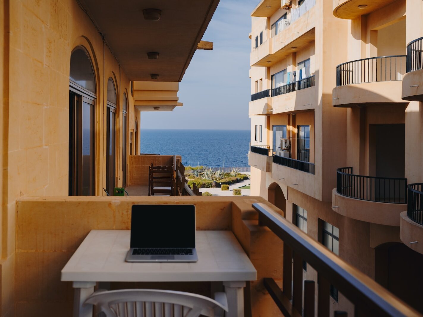 macbook pro on white table overlooking an ocean